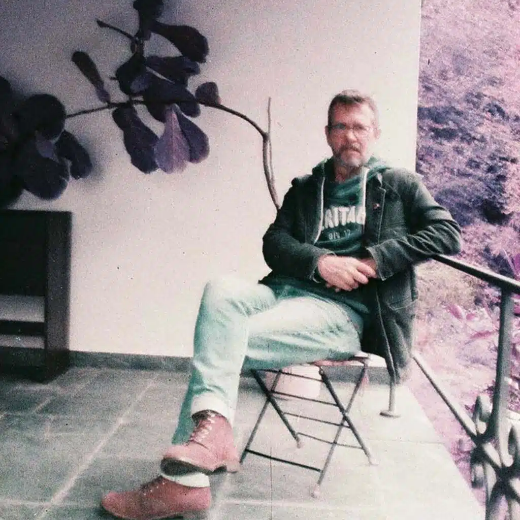Ein Mann sitzt auf einem Stuhl und schaut in die Kamera